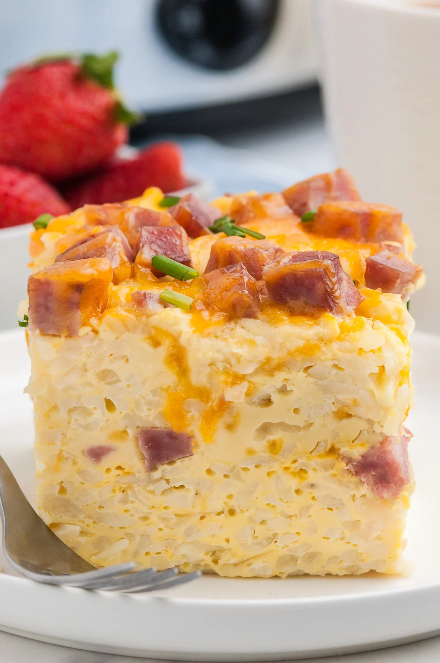 individual slice of ham and cheddar casserole served on a white plate with a lip.