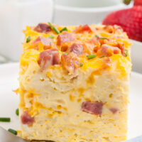 huge slice of breakfast casserole. Tall slice of egg casserole with ham and cheddar.