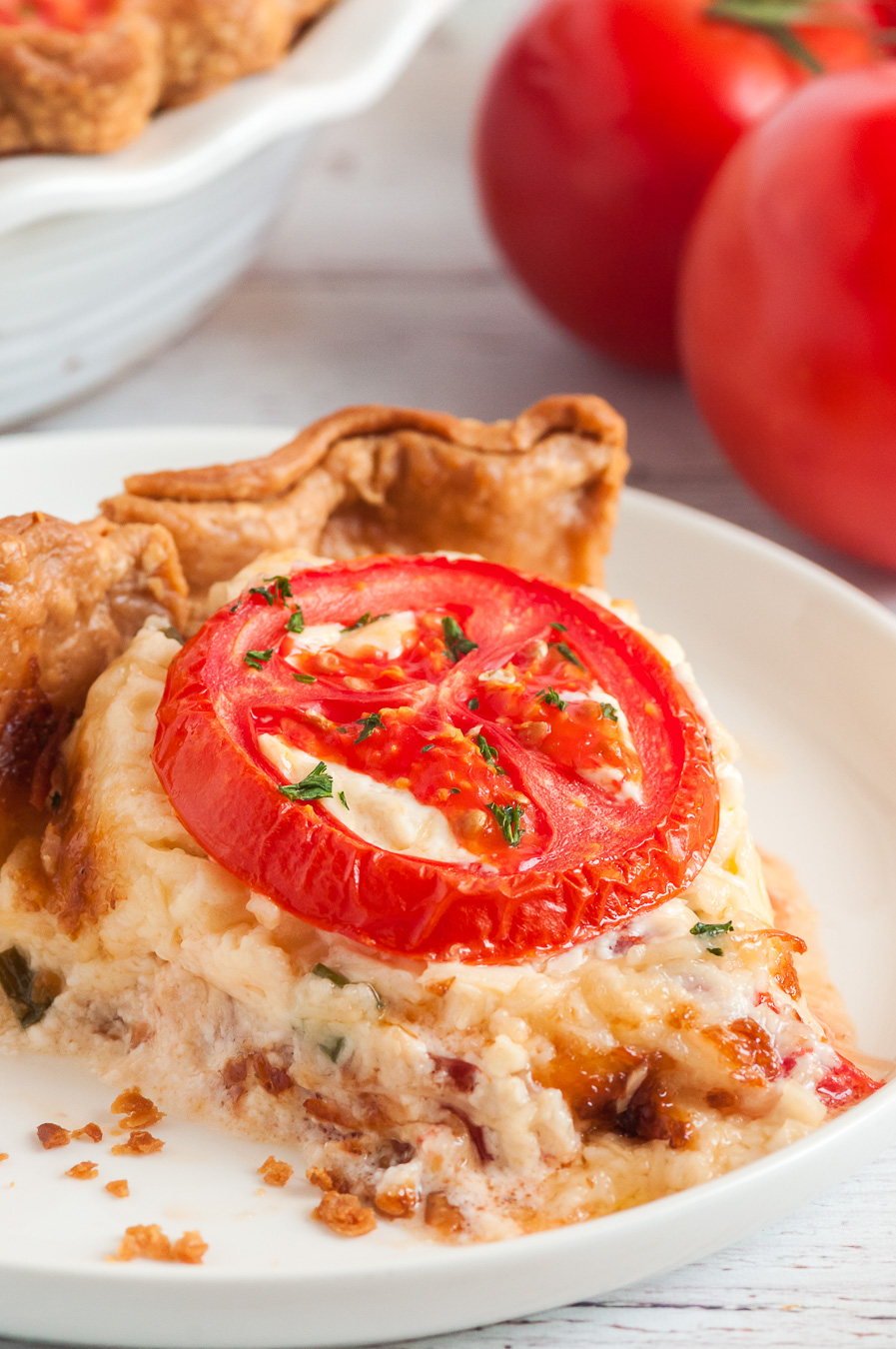 tomato pie on a serving dish with a tomato garnish