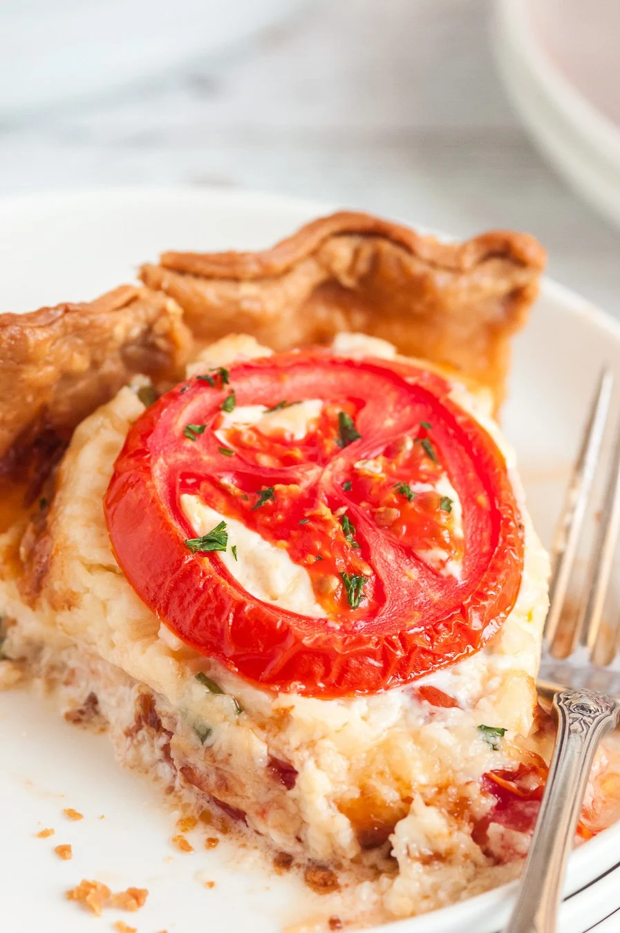tomato pie slice up close with fresh tomato garnish