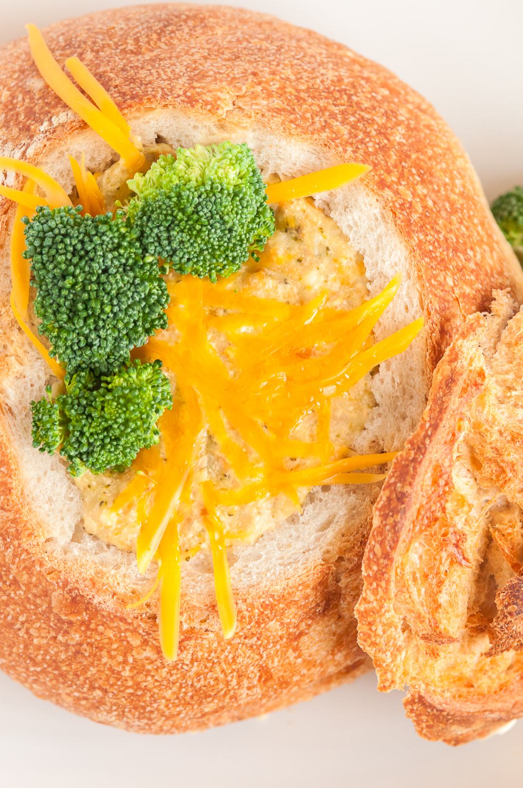 delicious soup inside of a bread bowl with cheddar and broccoli garnish