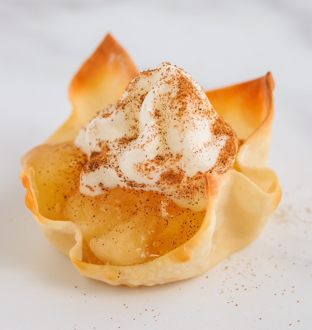 apple pie cups up close with apple pie filling, whipped cream and cinnamon