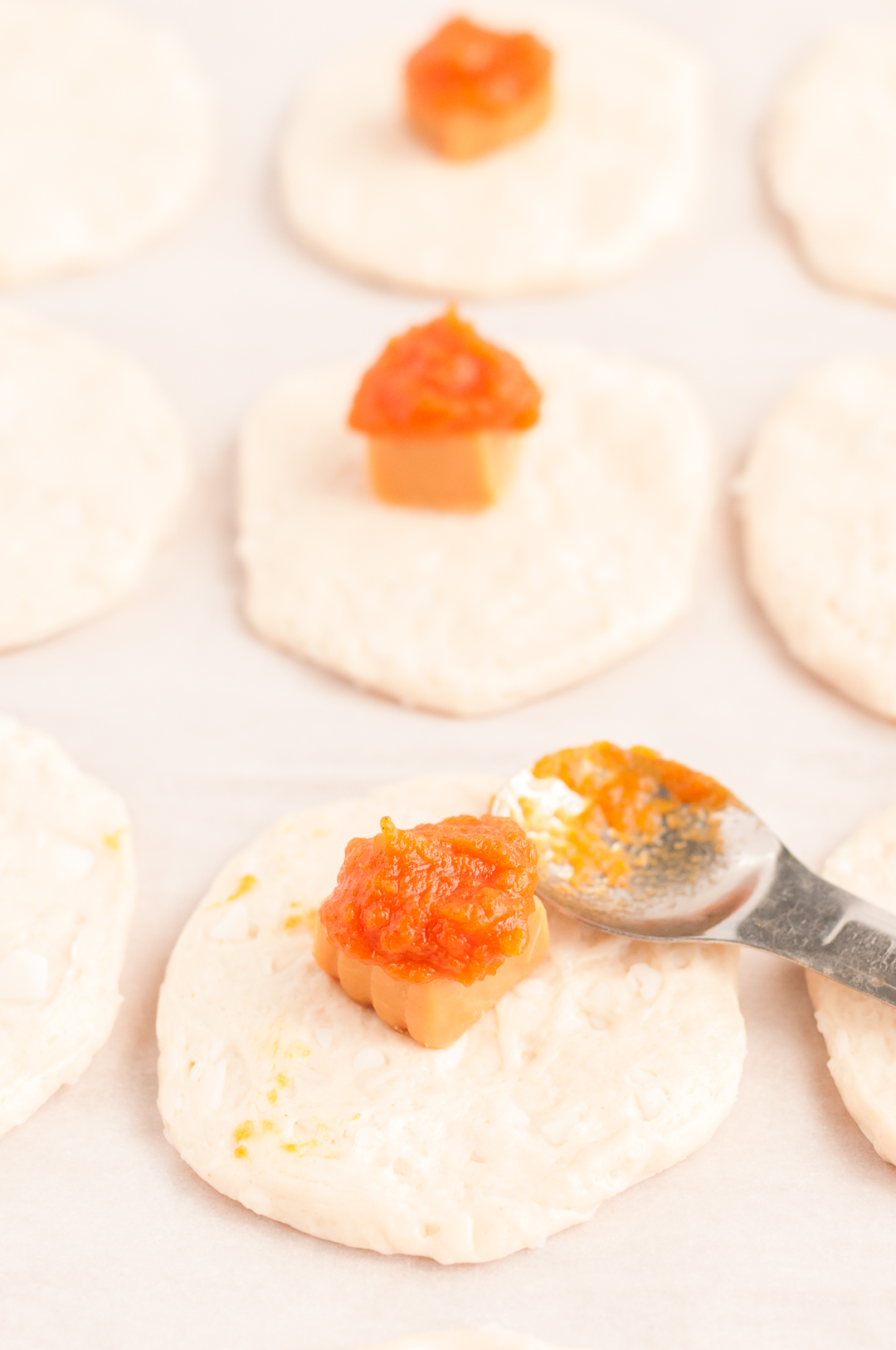 adding pumpkin pie filling to mini pie dough