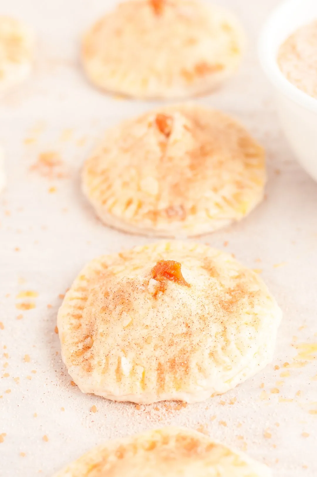 adding sugar and spice blend to mini pies