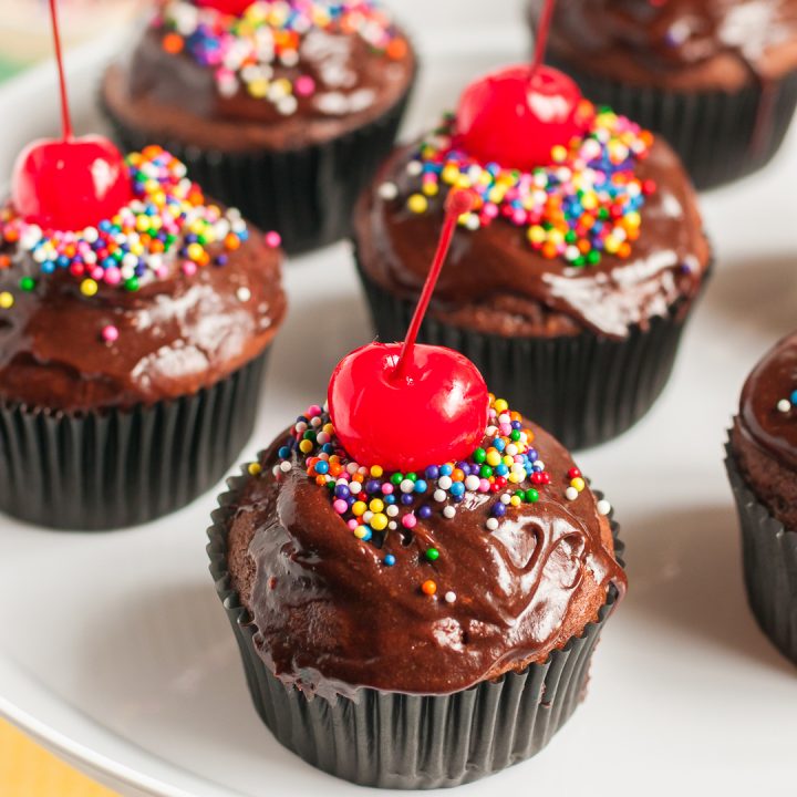 Chocolate cupcakes with big cherries on top.