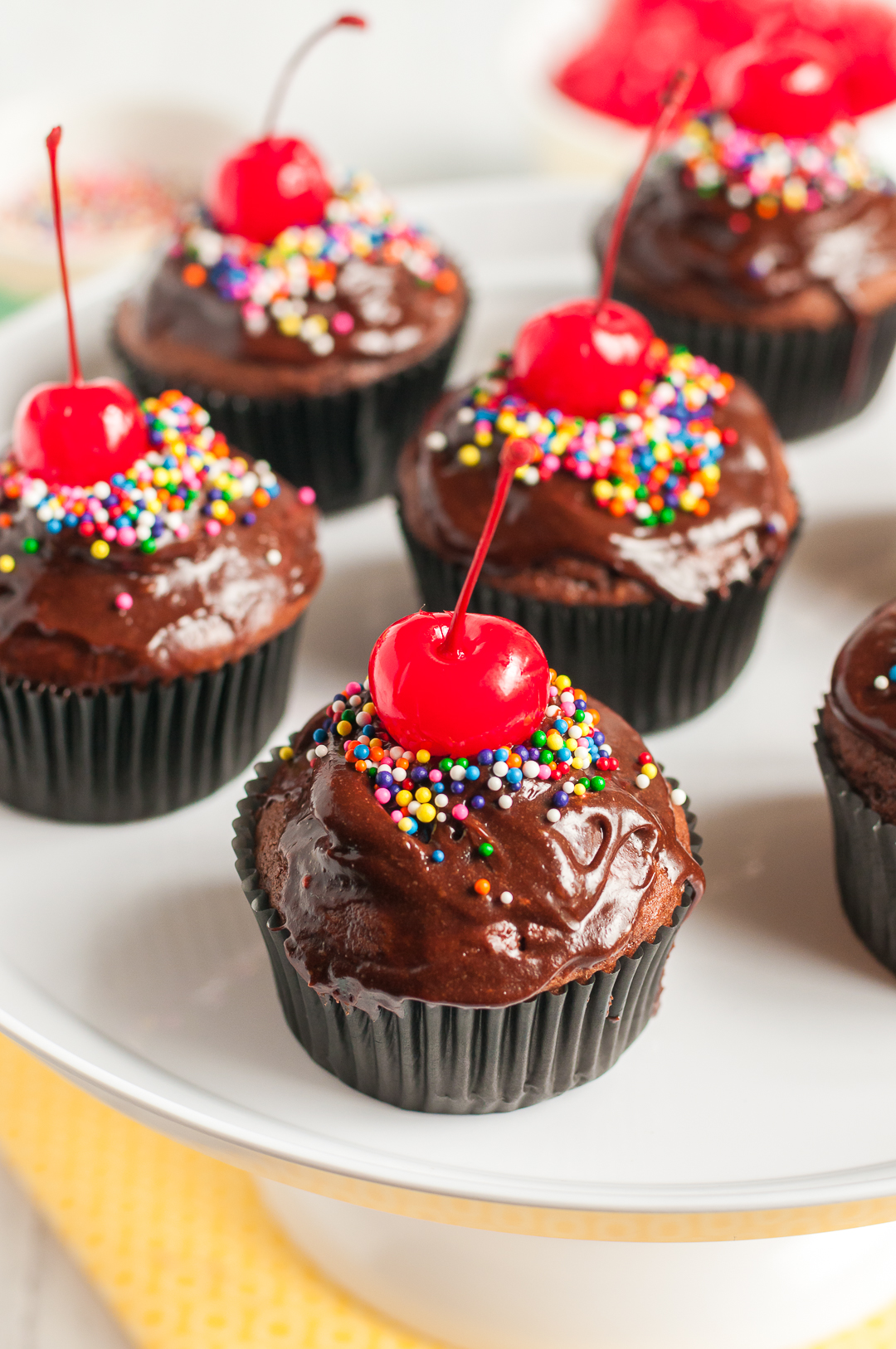 Chocolate cupcakes with big cherries on top.