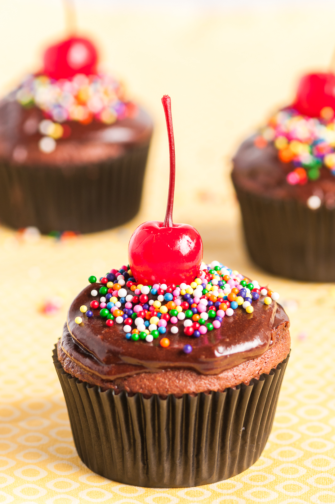 pretty chocolate cupcakes with chocolate frosting, sprinkles and cherries