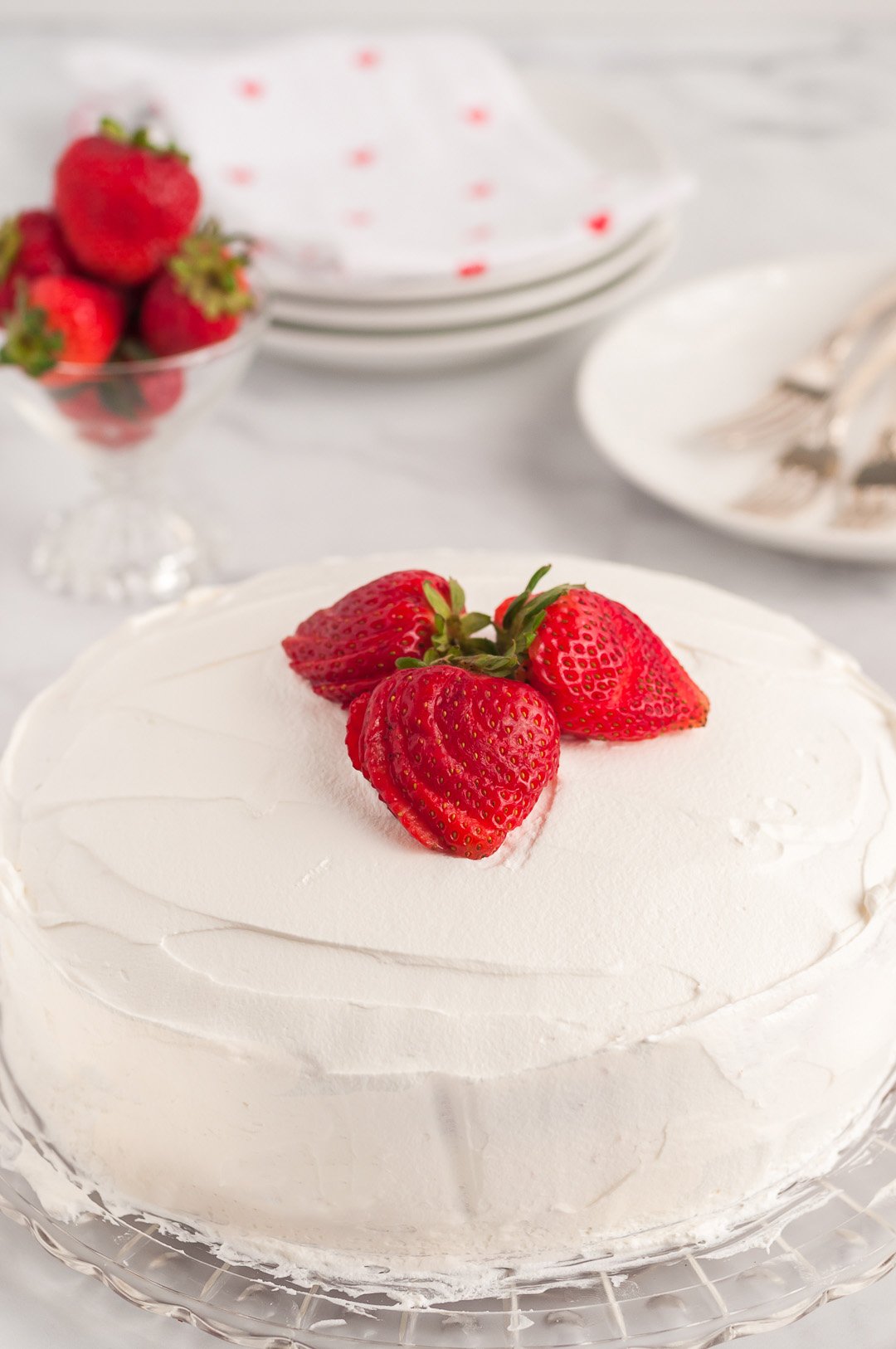 frosted cake topped with sliced strawberries