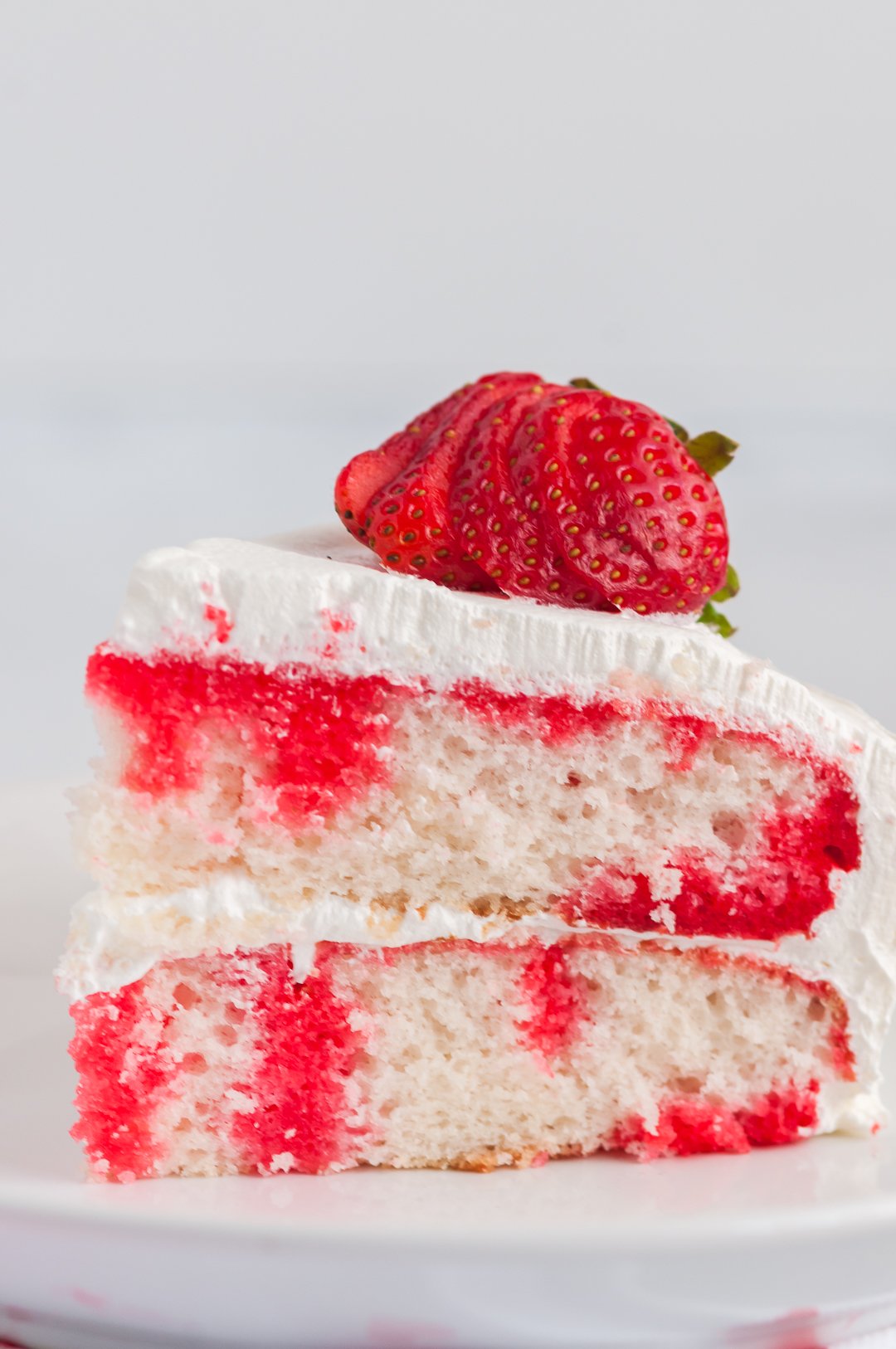 slice of strawberry poke cake on a plate