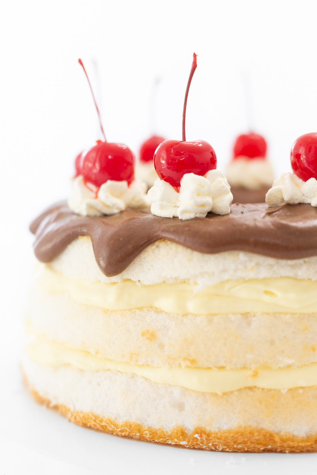 Giant maraschino cherries o top of layered boston cream cake.