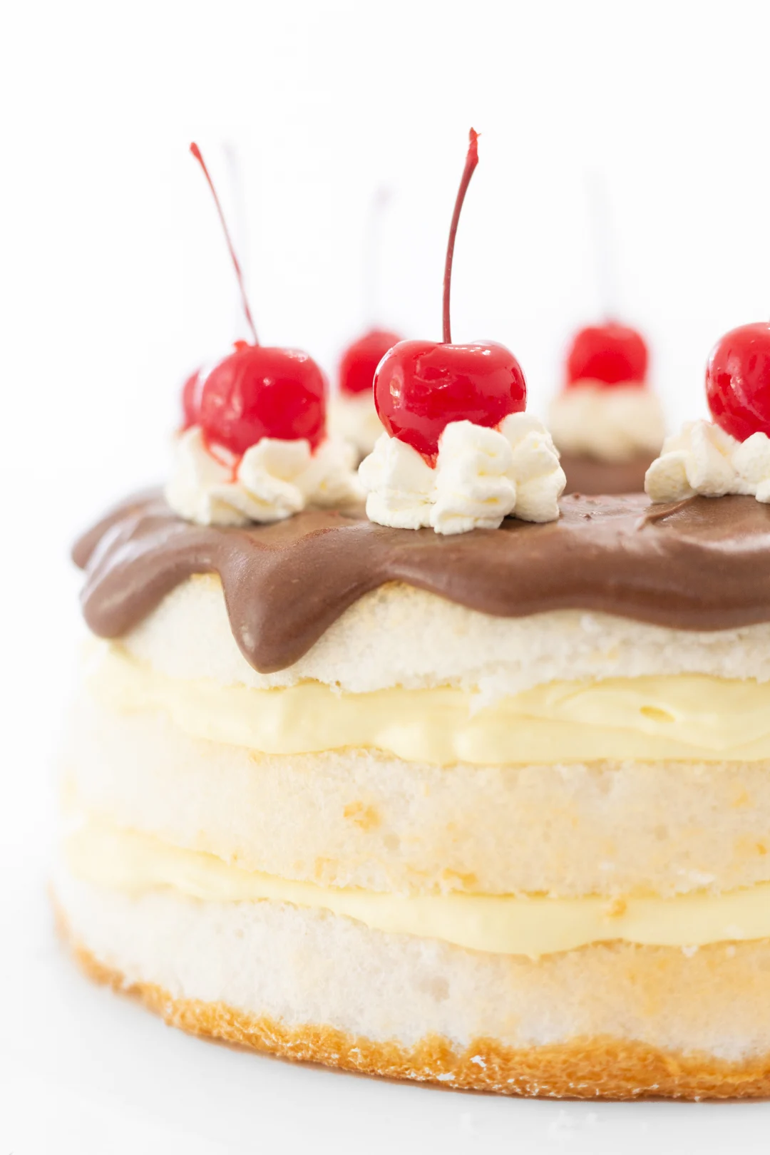 Giant maraschino cherries o top of layered boston cream cake.