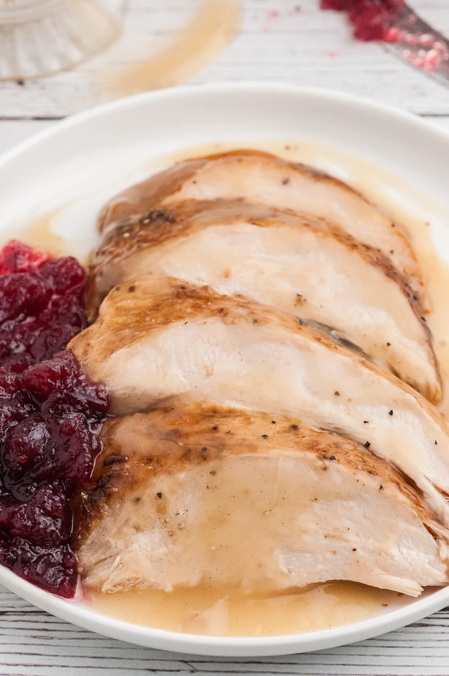 sliced turkey on a plate served with cranberry sauce
