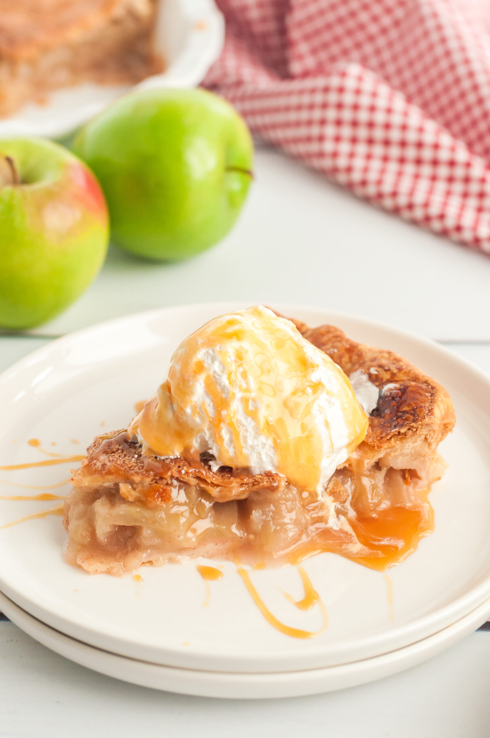 warm slice of apple pie being served with ice cream and caramel drizzle
