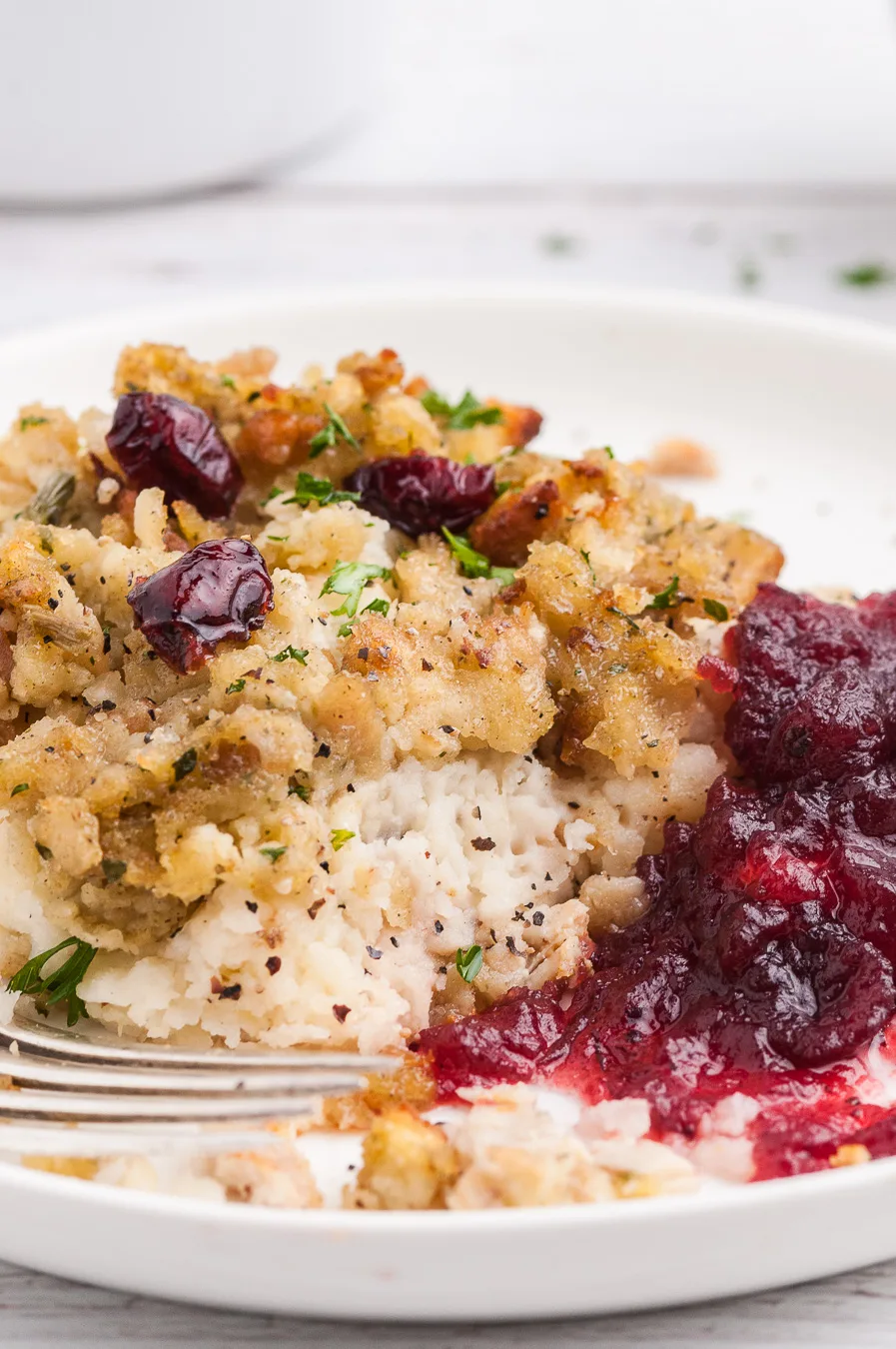 serving of stuffing casserole on a plate with cranberry sauce
