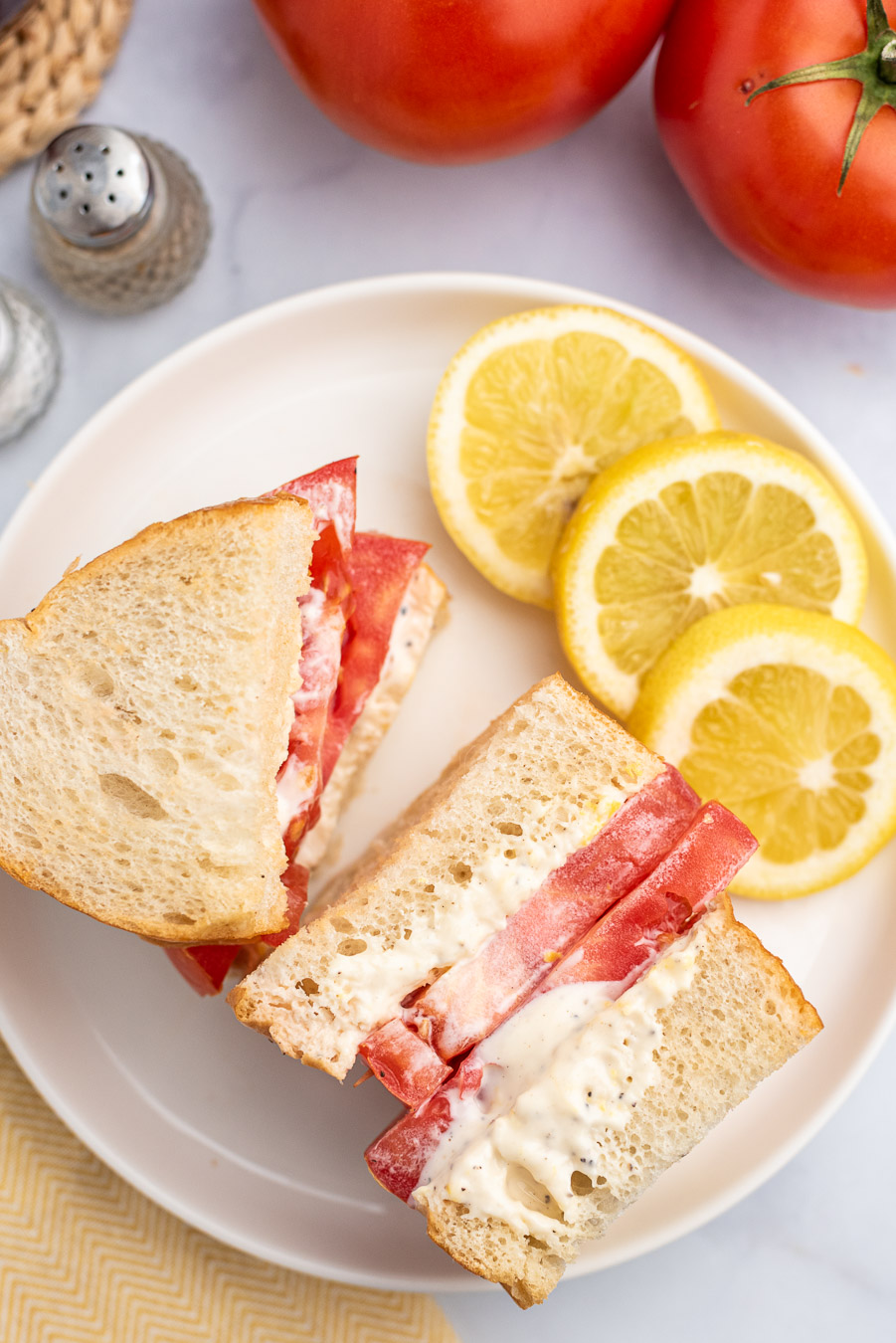 tomato sandwich with a lot of mayo on thick bread, lemon slices on the side