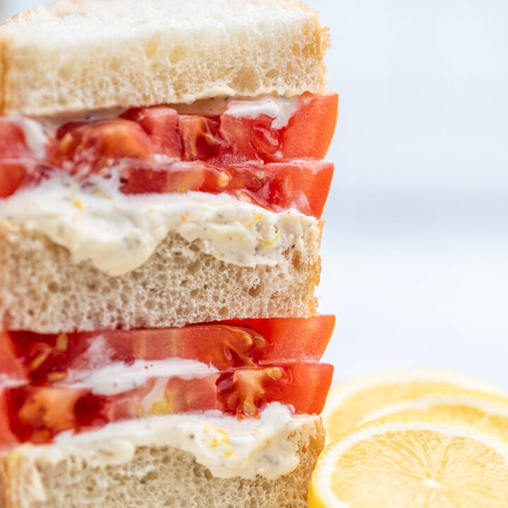 stacked tomato sandwich with lemon slices on the side