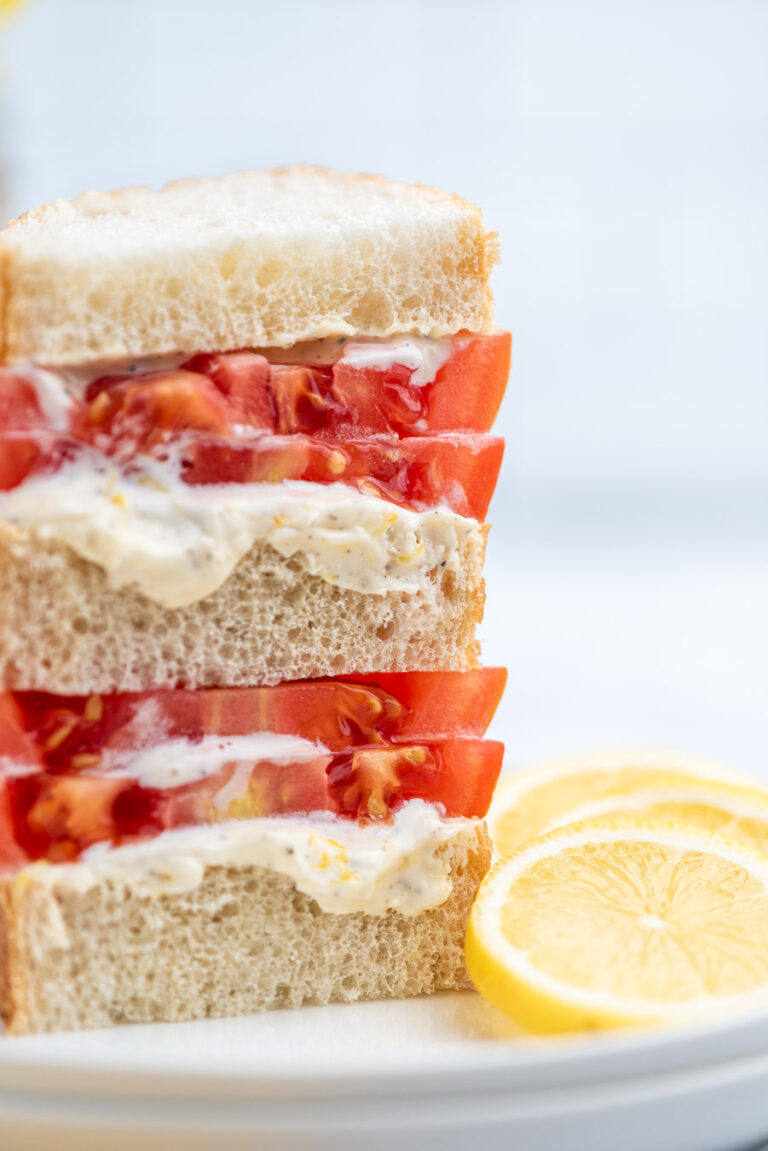 stacked tomato sandwich with lemon slices on the side