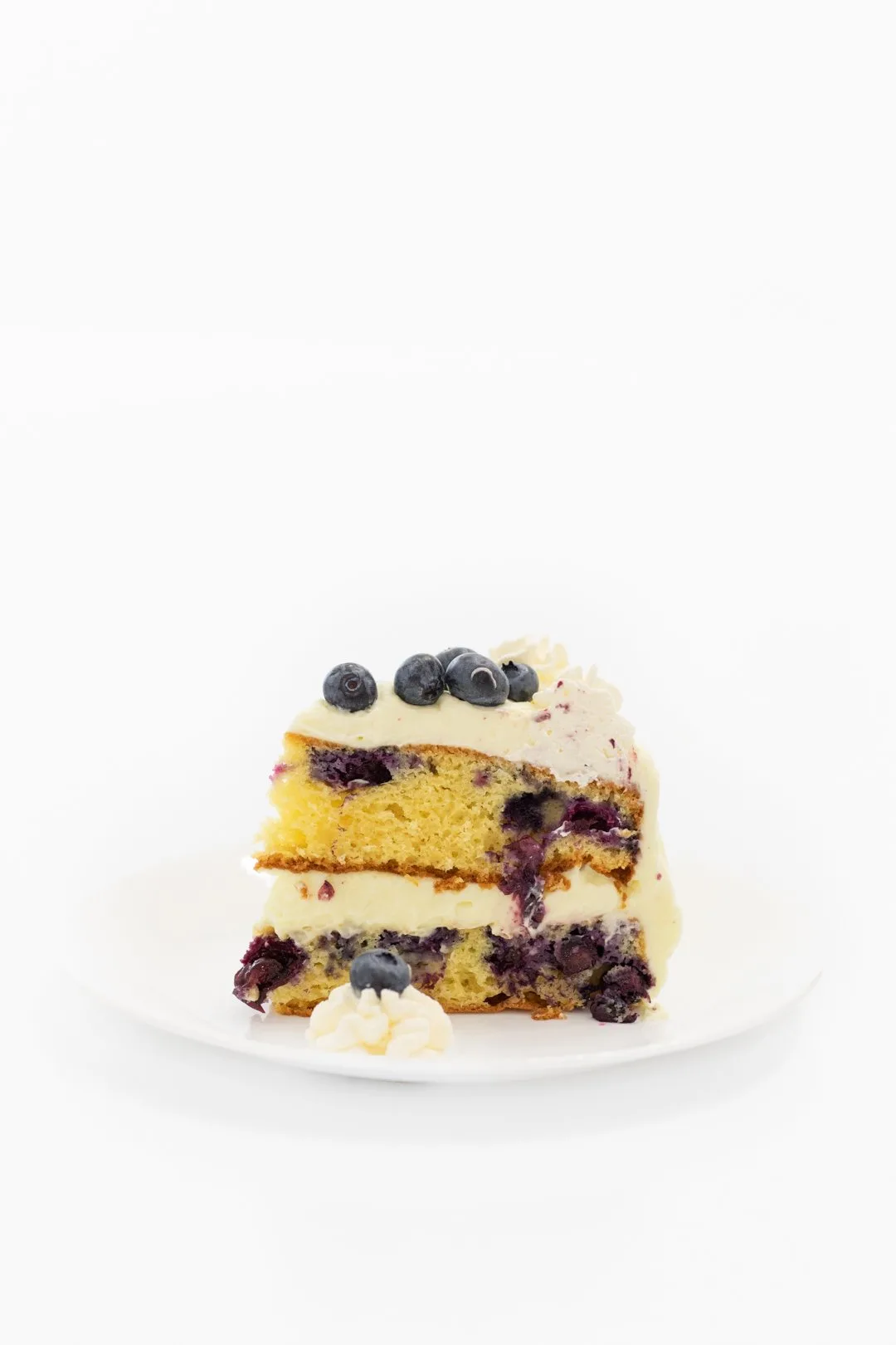 Tall slice of blueberry cake with fresh blueberries
