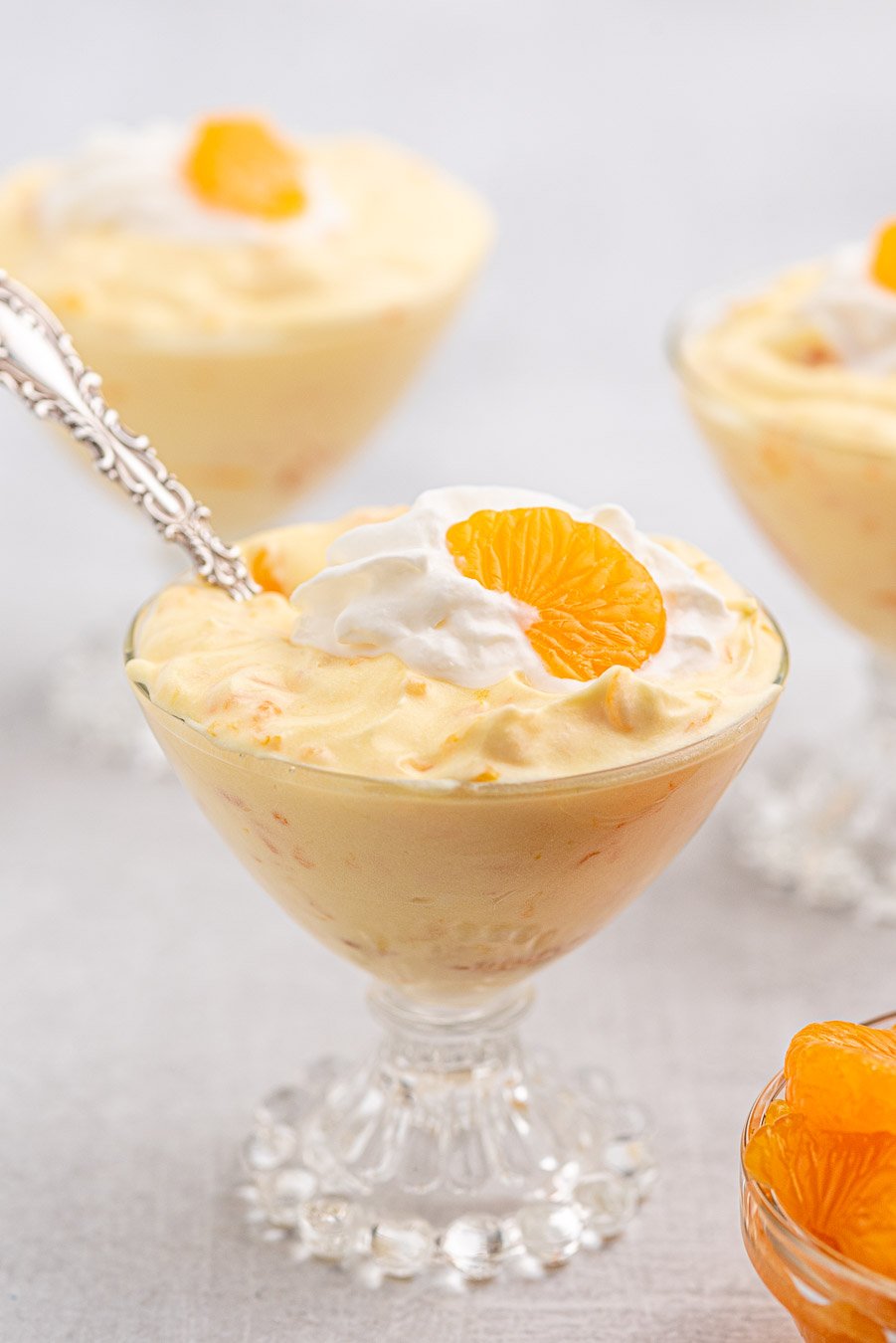 pretty mandarin orange  pudding dessert in individual vintage glasses served with a spoon.