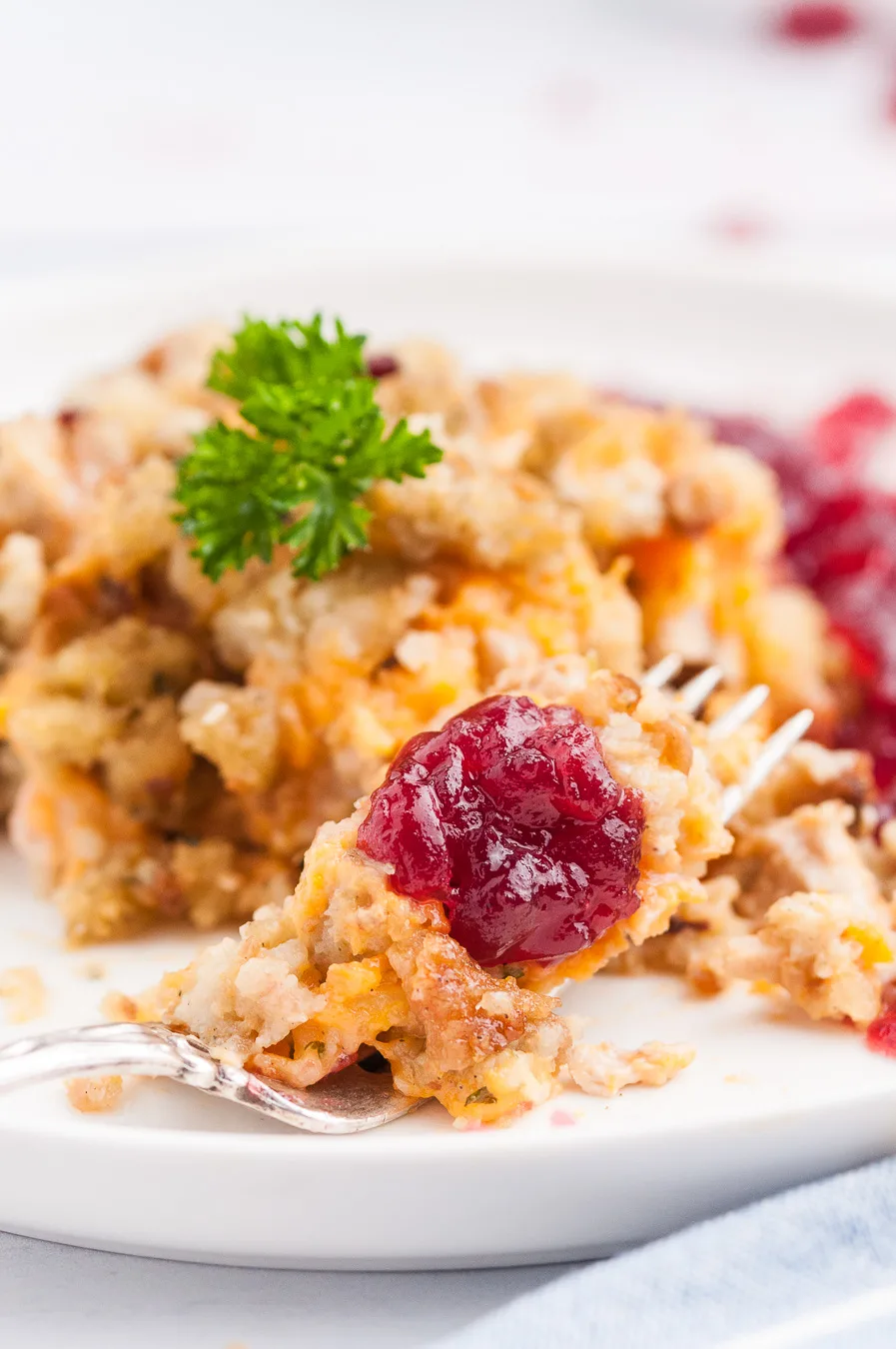 fork full of stuffing casserole with cranberry sauce