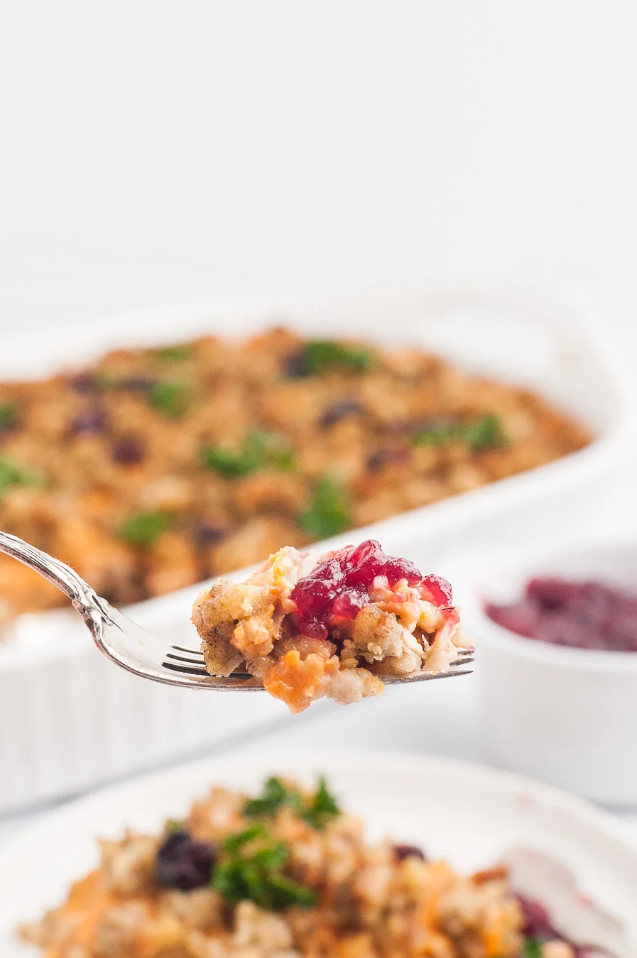 fork full of stuffing casserole with a dab of cranberry sauce