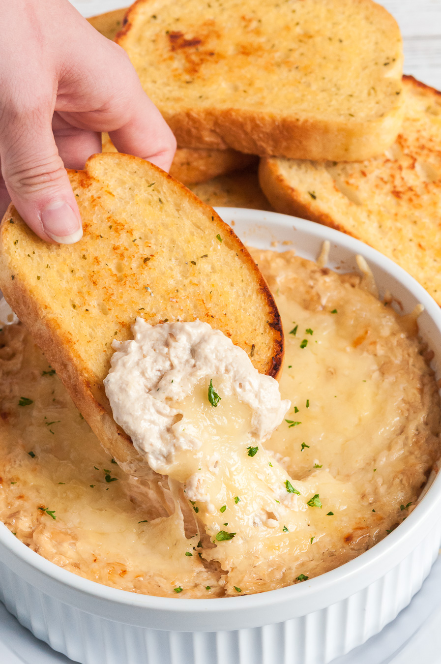 dipping a piece of garlic bread into french onion dip