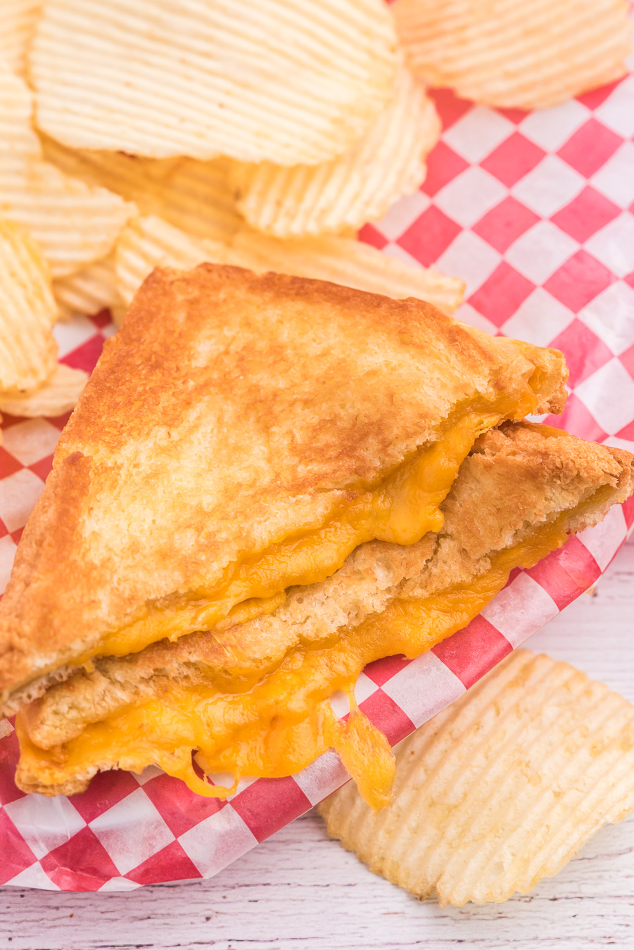 grilled cheese with extra cheese oozing out of it. Served on restaurant style checkered wax paper and ruffled chips