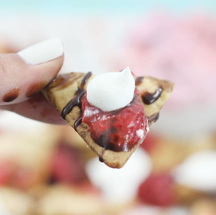 Pie Crust Nachos using baked Pie Crust cut into tortilla shaped and topped with Berry infused Whipped Topping, Strawberry sauce & Chocolate drizzle.