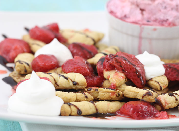 Pie Crust Nachos using baked Pie Crust cut into tortilla shaped and topped with Berry infused Whipped Topping, Strawberry sauce & Chocolate drizzle.