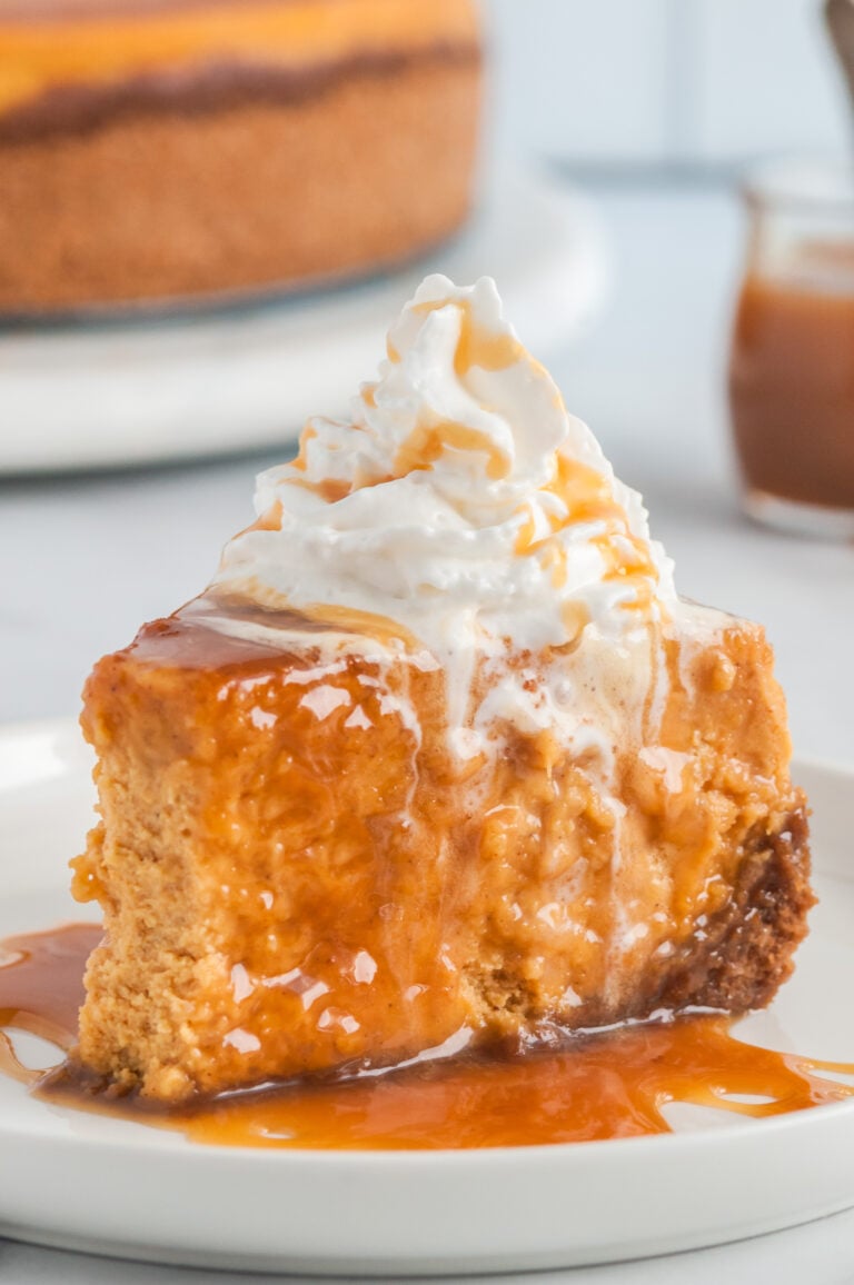 plated slice of pumpkin cheesecake with caramel sauce and whipped cream on top