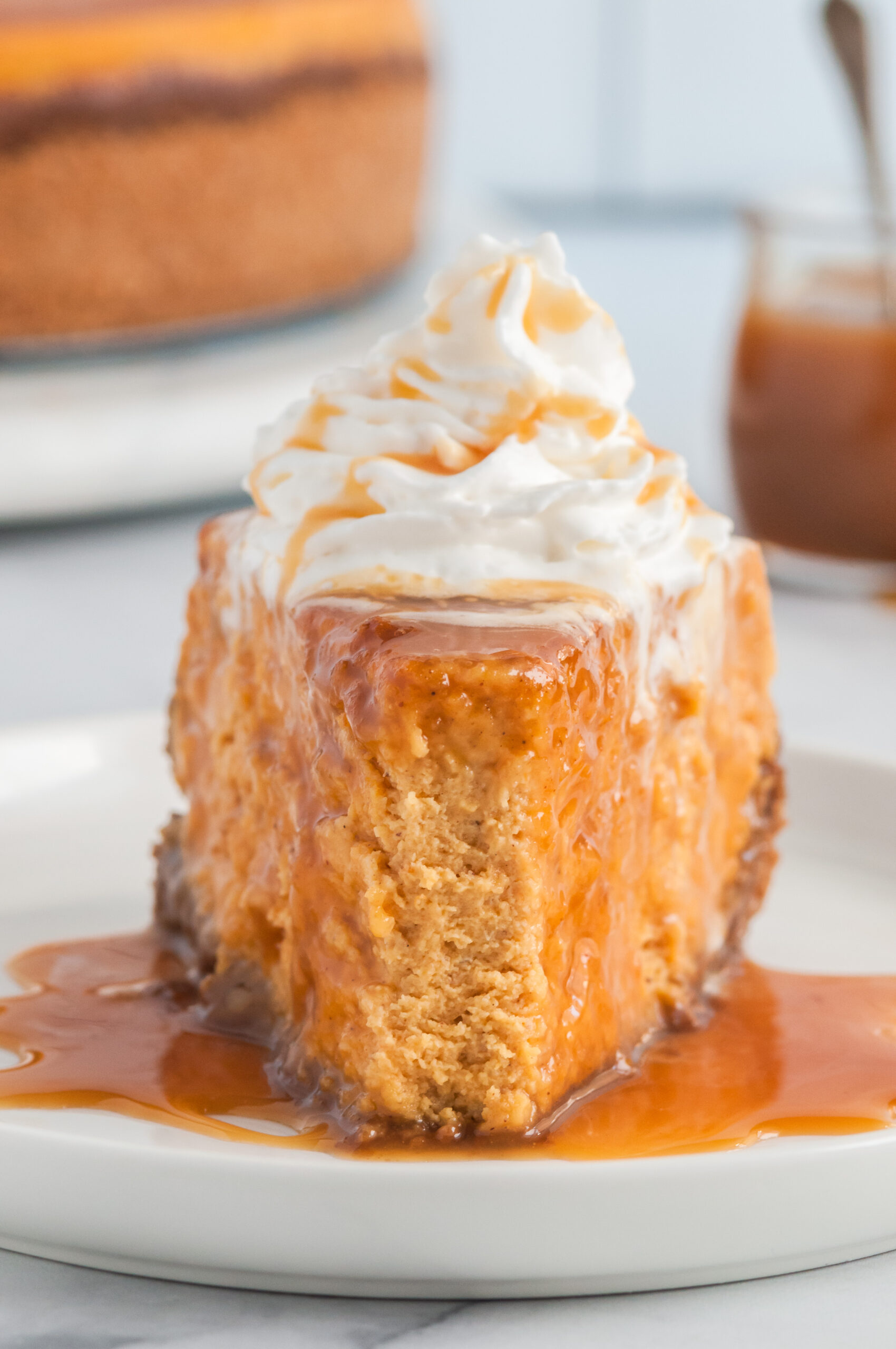 slice of pumpkin pie with fork bite taken out of it. Drizzled with caramel and whipped cream. Ginger crust.