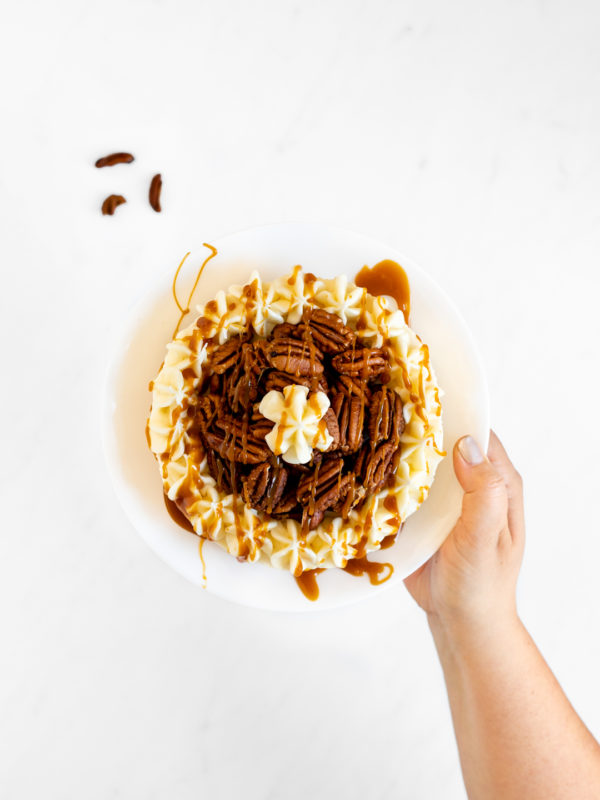 Caramel Pecan Cheesecake Being Held By Woman.