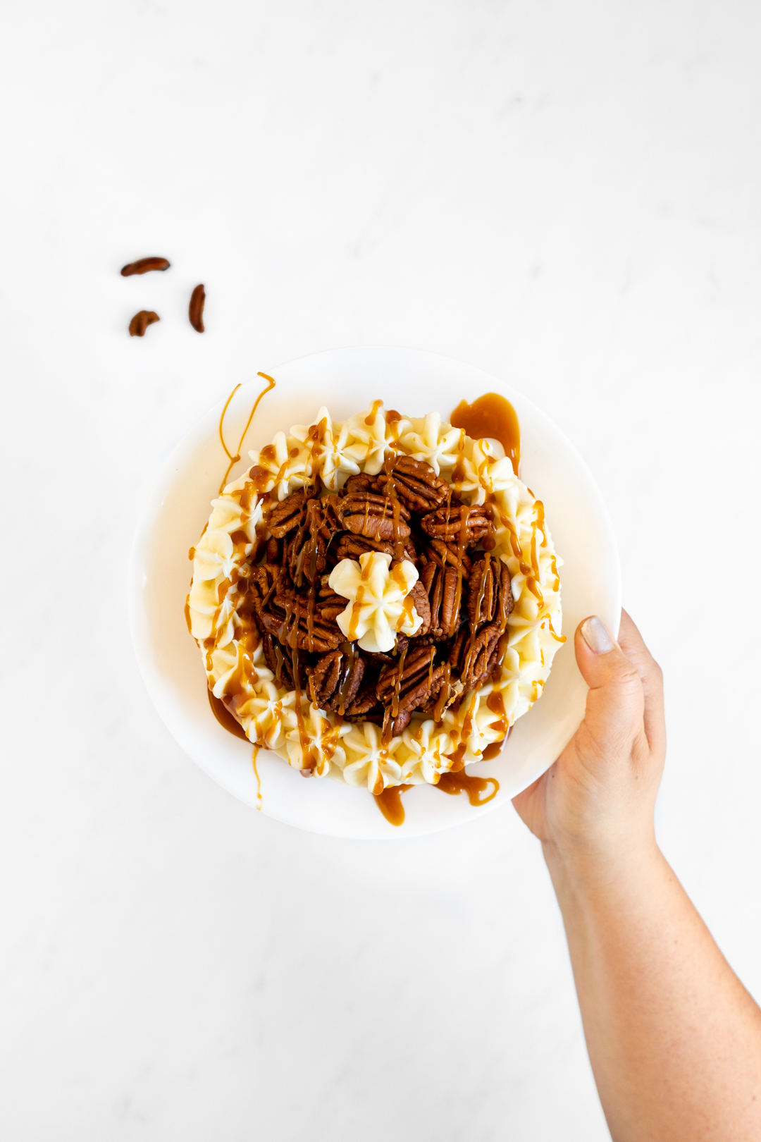 Caramel Pecan Cheesecake Being Held By Woman.