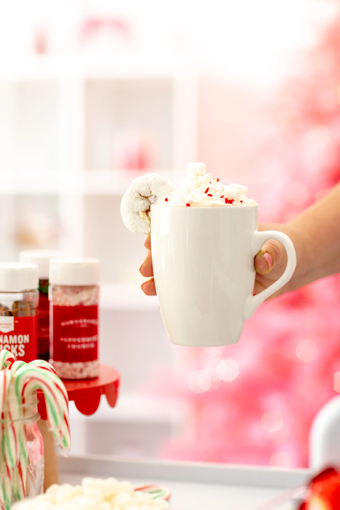 holding mug with whipped cream and candy cane
