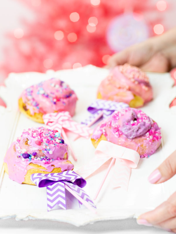 Pink and purple cinnamon roll lollipops with bows.