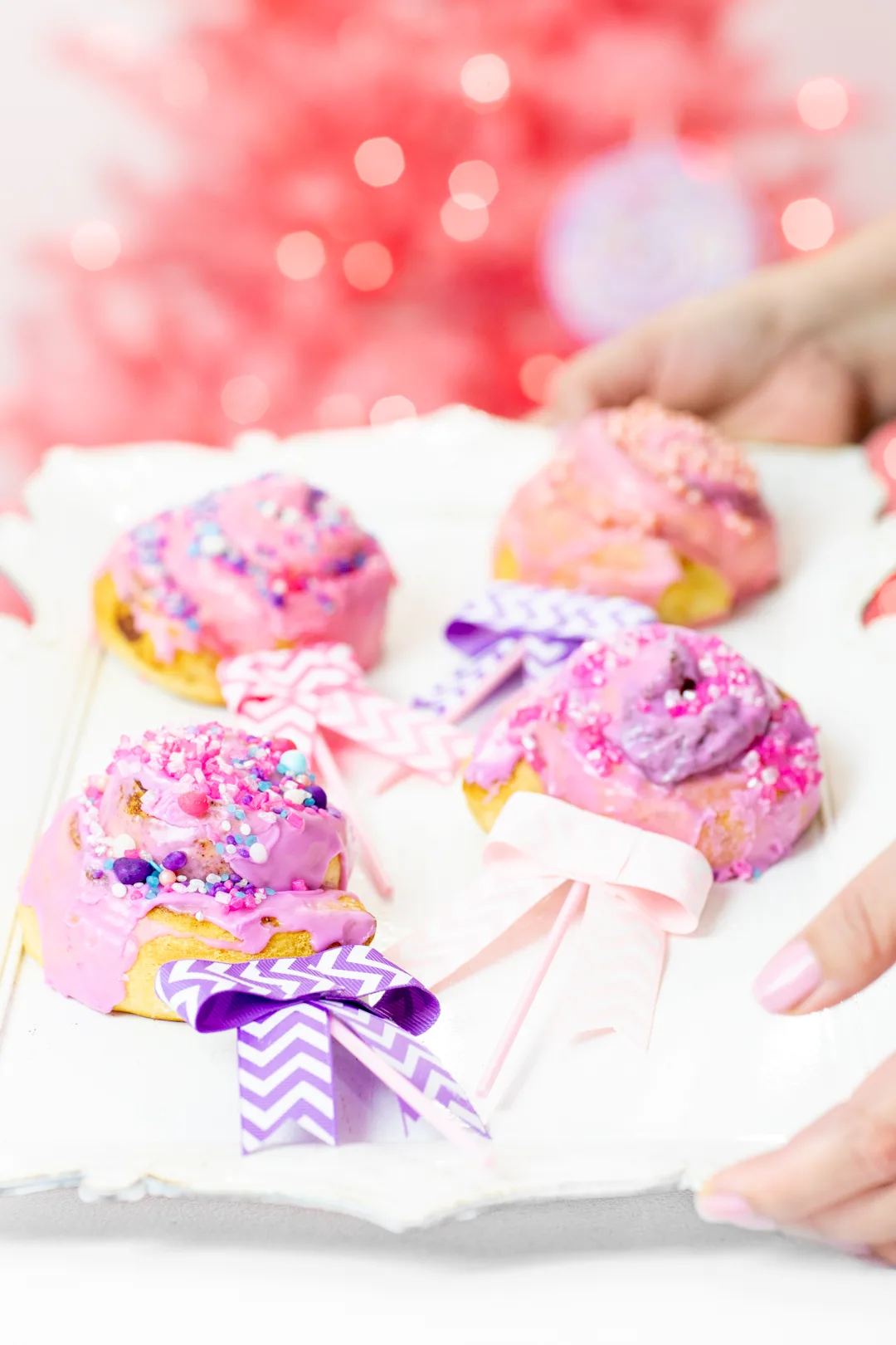 Pink and purple cinnamon roll lollipops with bows.