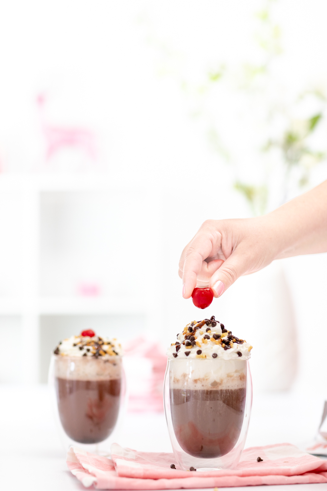 placing cherry on top of hot cocoa and whipped cream