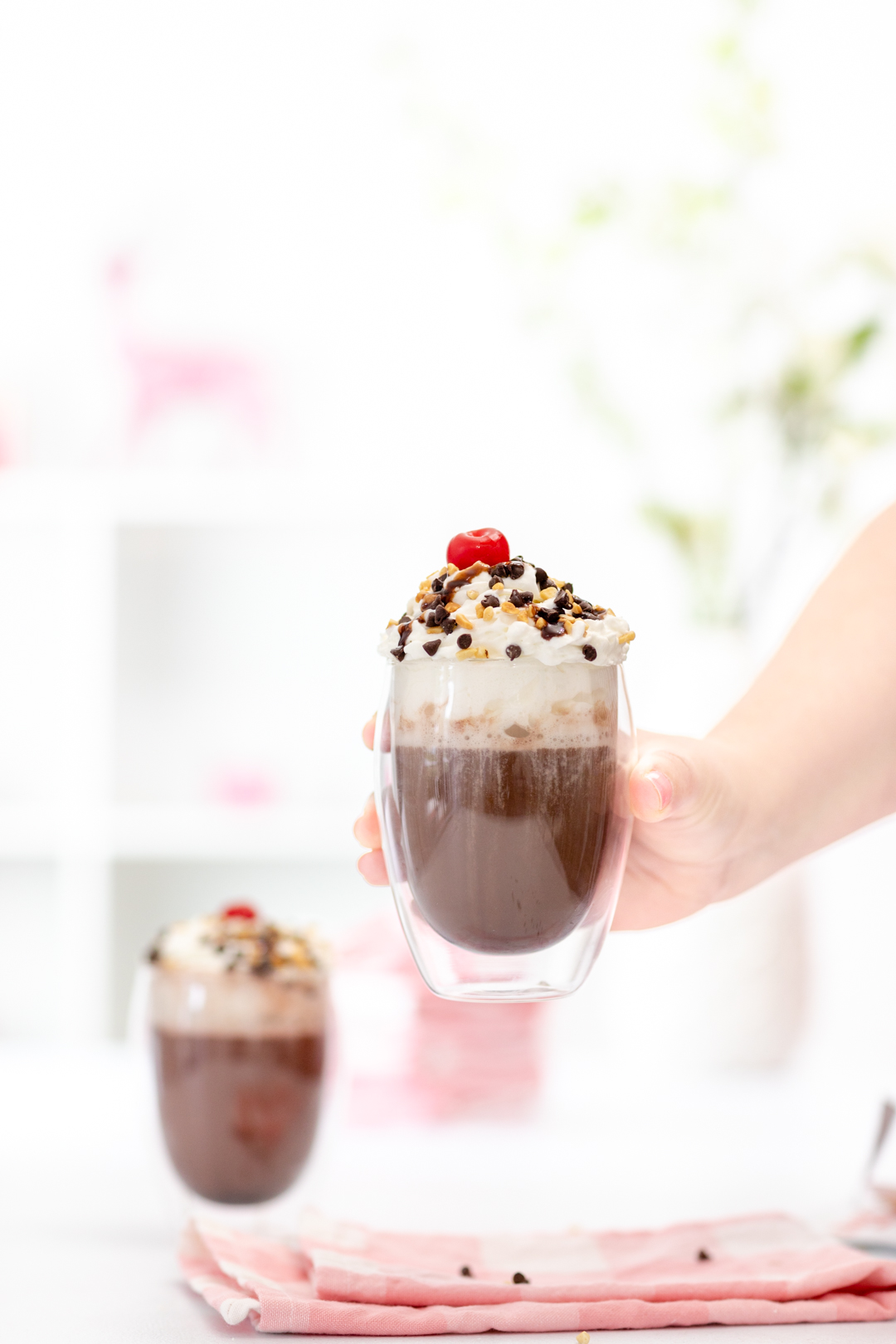 hot cocoa with whipped cream, chocolate chips and a cherry