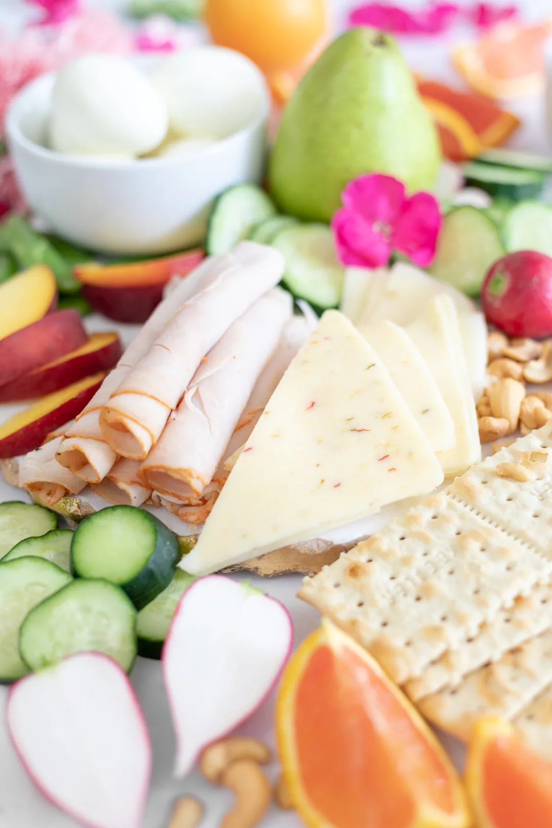 large lunch food spread with cheese slices, turkey, vegetables and crackers