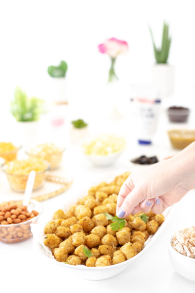 adding cilantro to bowl of potato tots