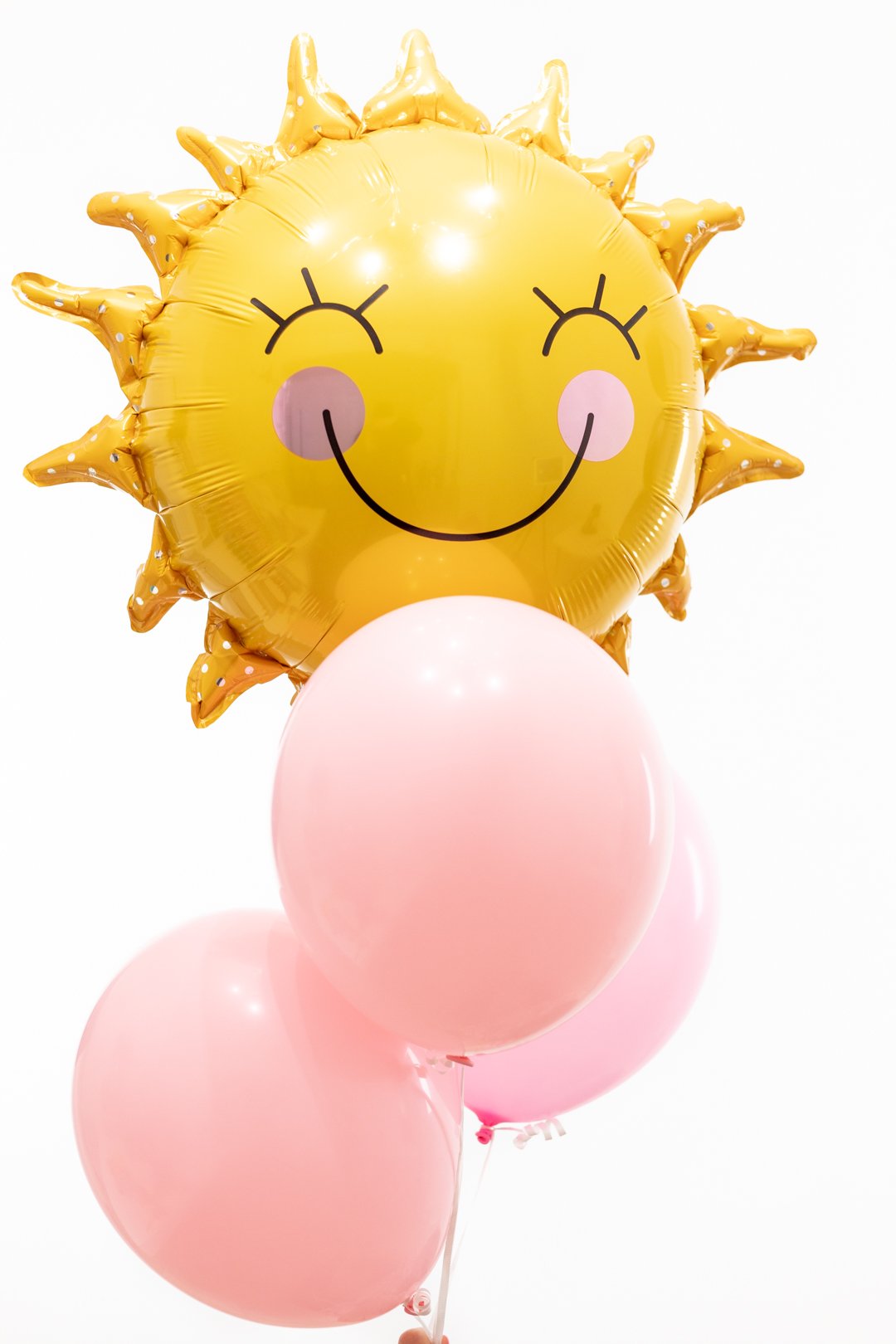 Sun balloon with pink cheeks and complimentary pink balloons.