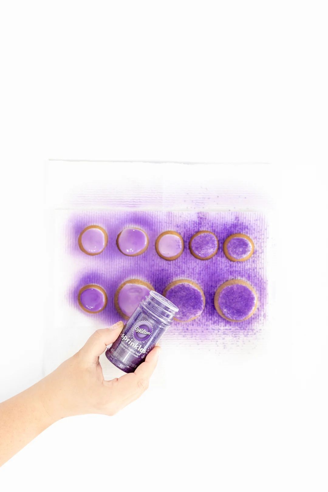 sprinkling purple sprinkles on cookies