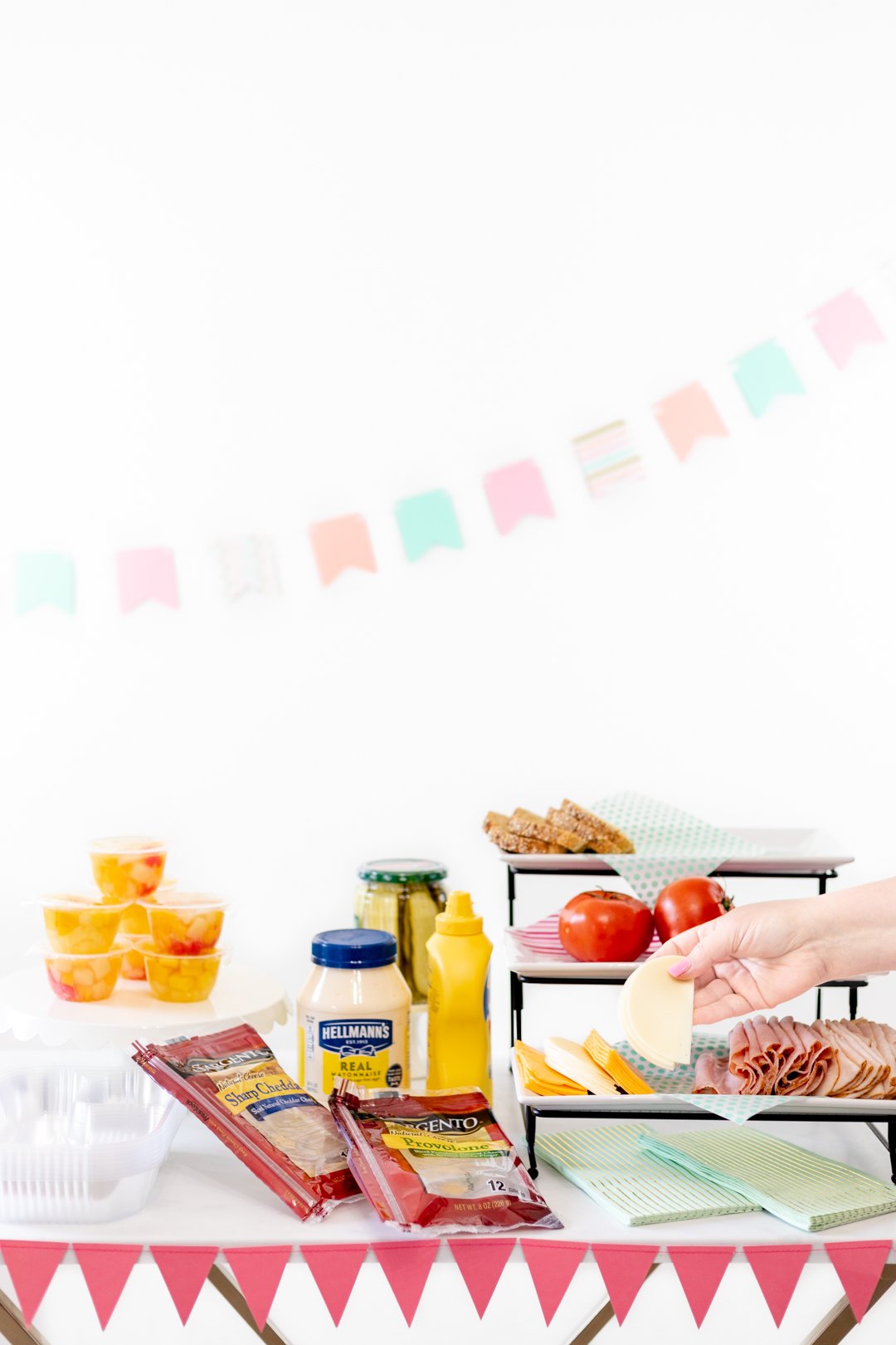 sandwich party spread with all the fixings and side options like fruit.