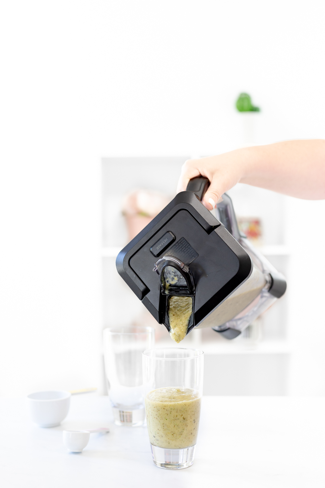 pouring green smoothie into glass