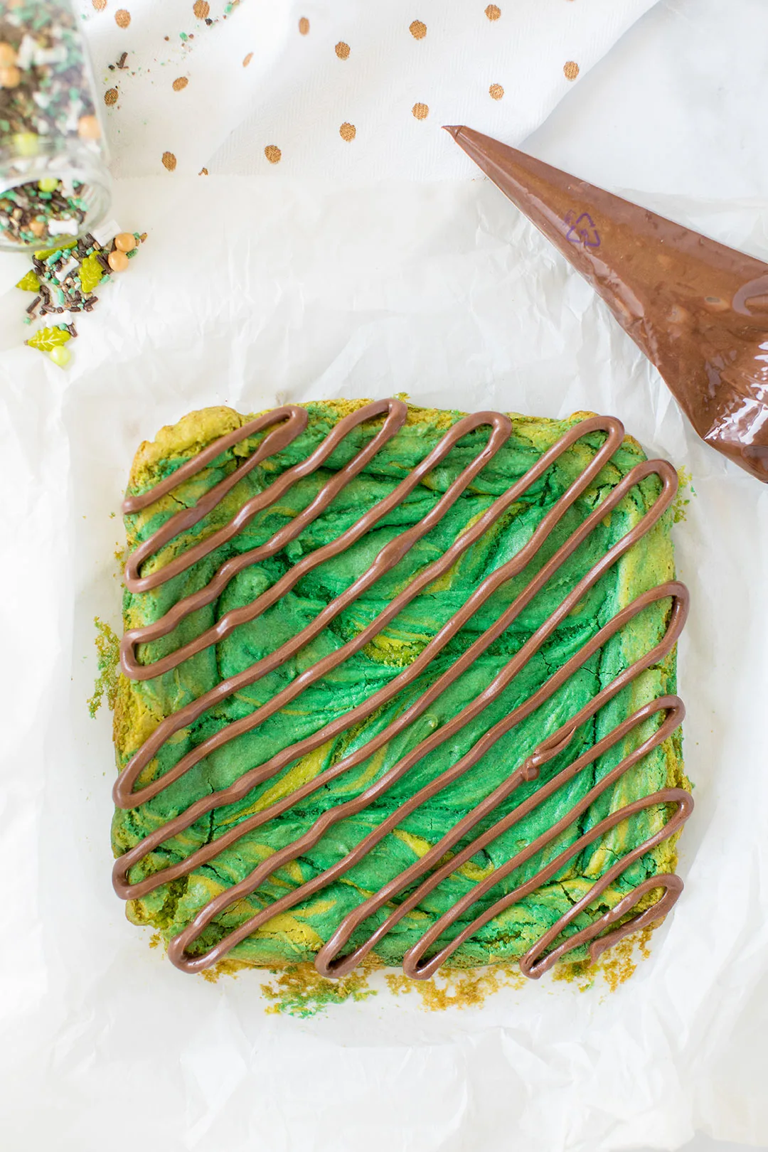 chocolate frosting drizzled on top of baked green colored blondies