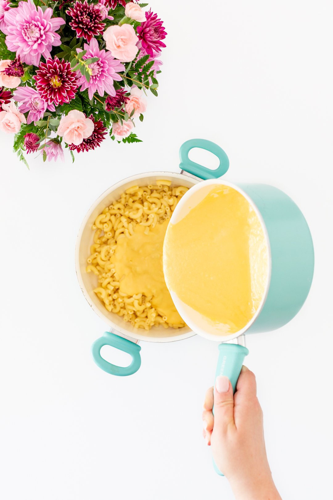 pouring cheese sauce into macaroni pan