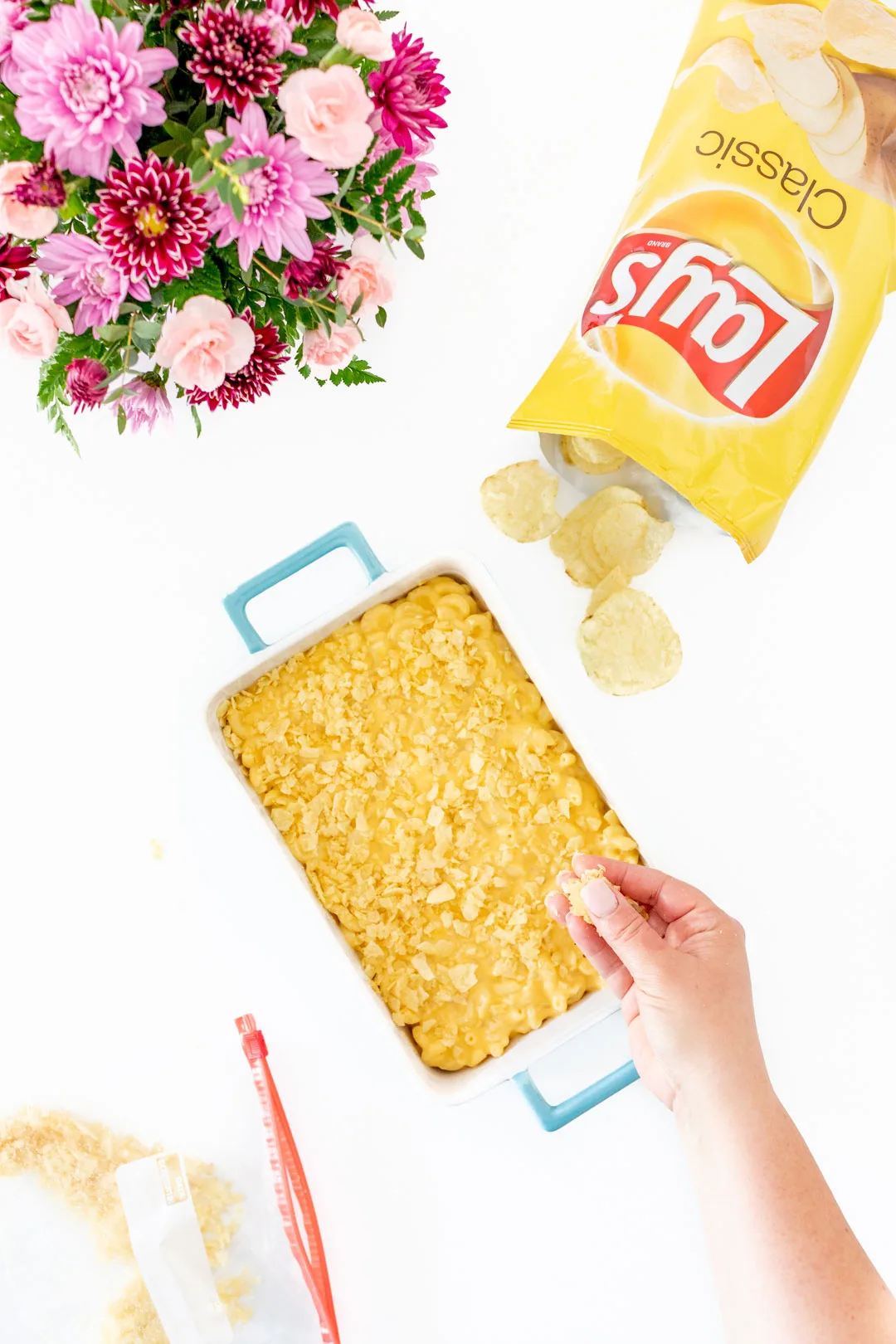 putting crushed potato chips on top of mac and cheese in a casserole dish