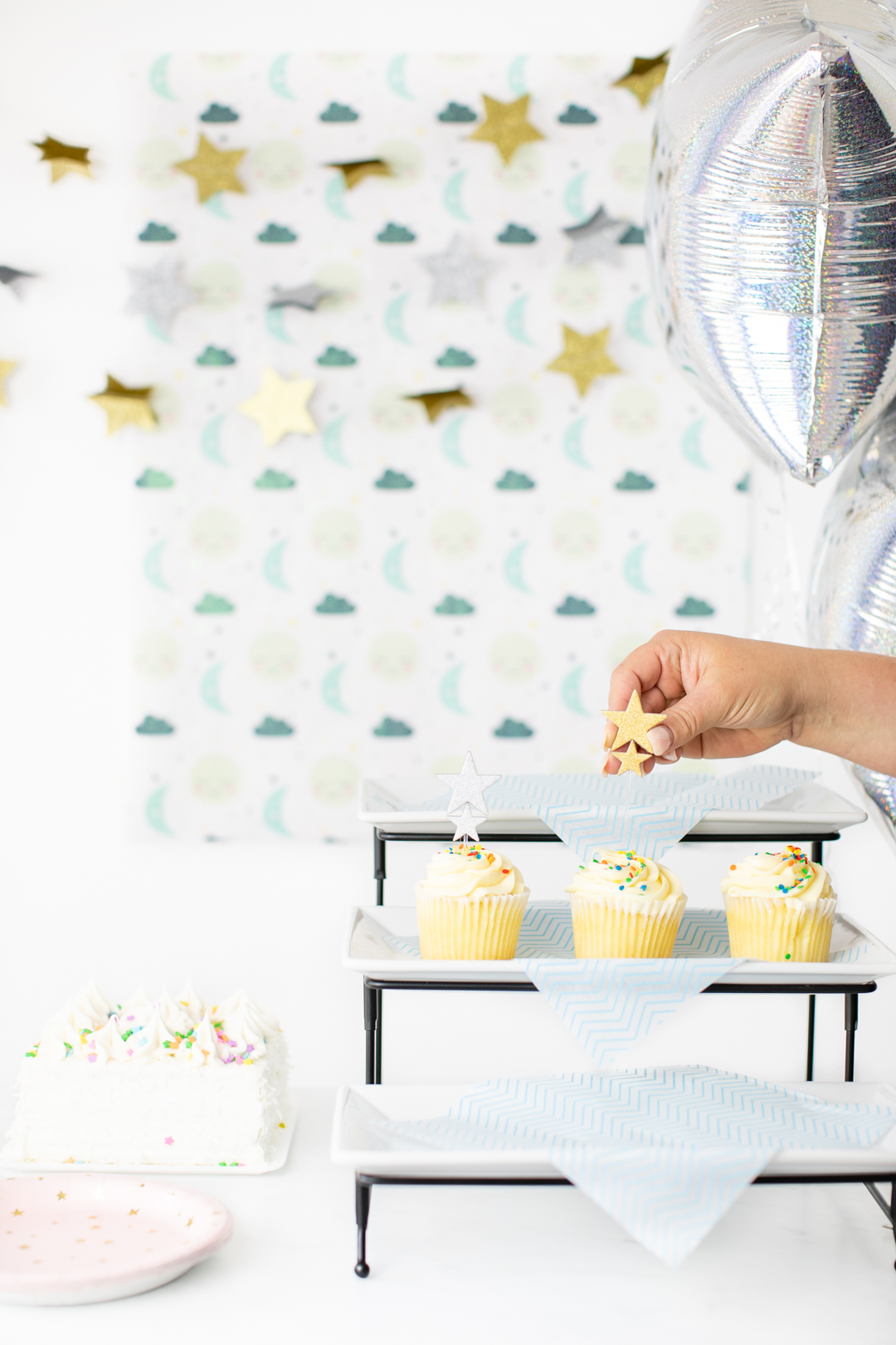 adding star cupcake topper to a cupcake