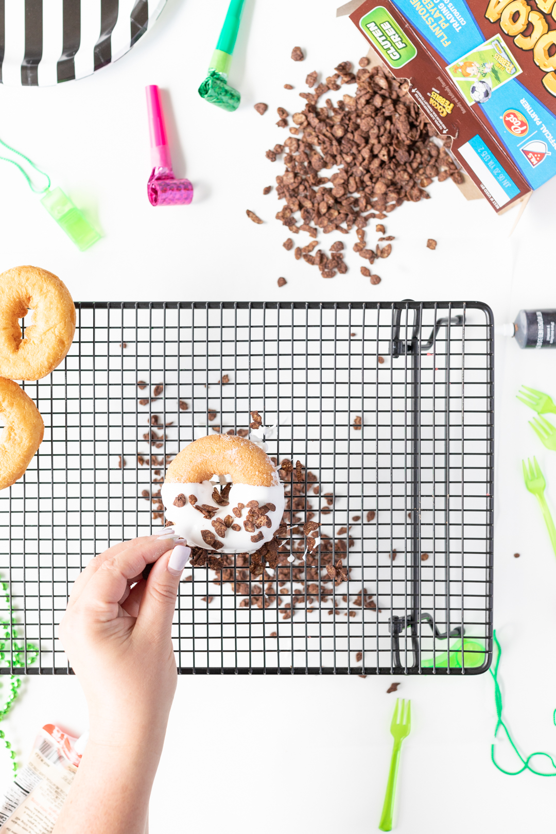 Sprinkling Cocoa Pebbles on Donuts