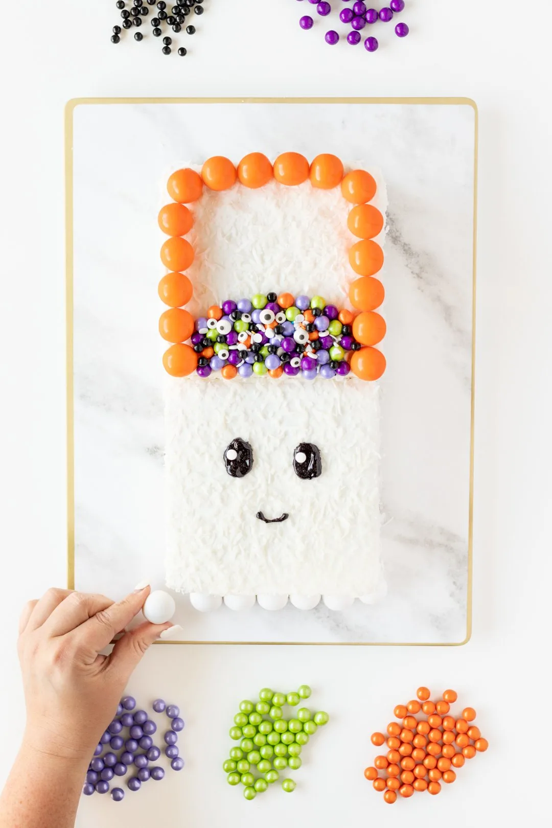 Adding gumballs to decorate a Halloween cake.
